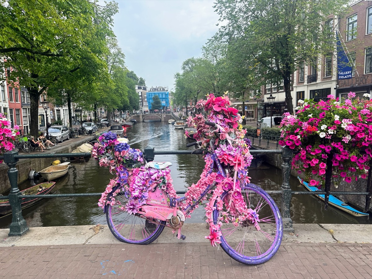 Cyclists riding along Amsterdam canal with historic buildings